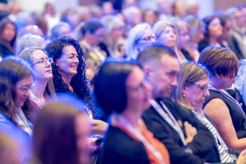 Audience members seated watching conference